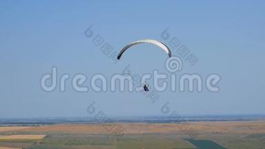 极端滑翔伞飞行在一个晴朗的蓝天，阳光照射到相机。 滑翔伞飞行体验跳伞